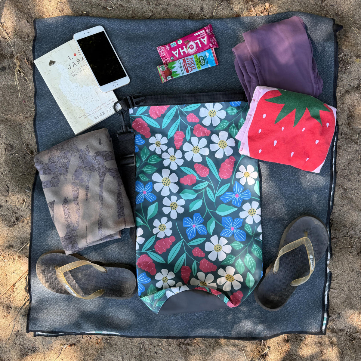 10L Dry bag surrounded by a bunch of packable items on sand