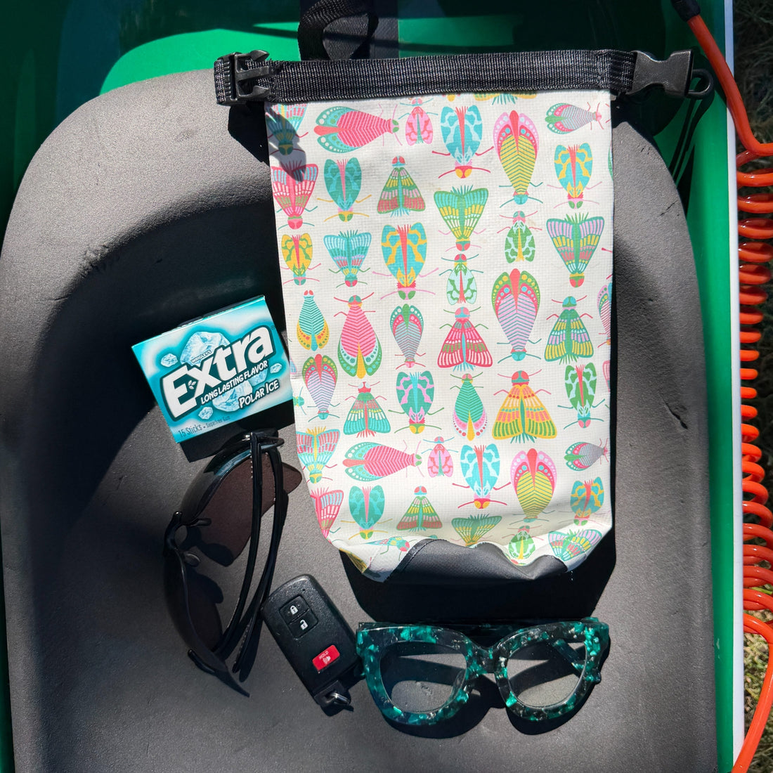 dry bag with moths on it surrounded by small items that fit in the dry bag