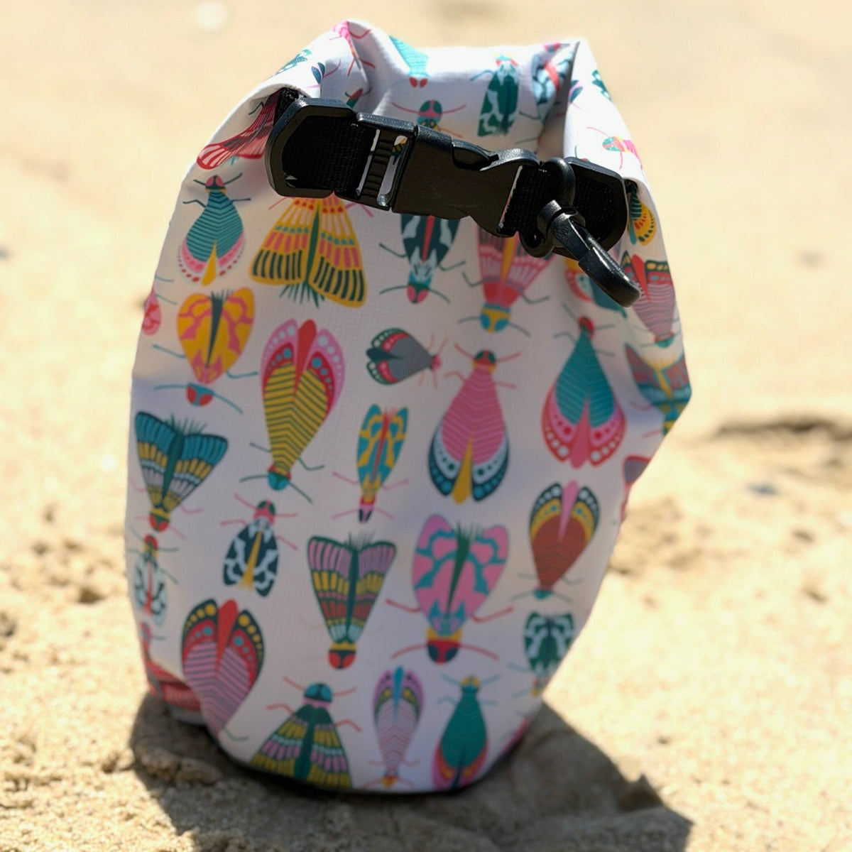small bug patterned dry bag on warm beach