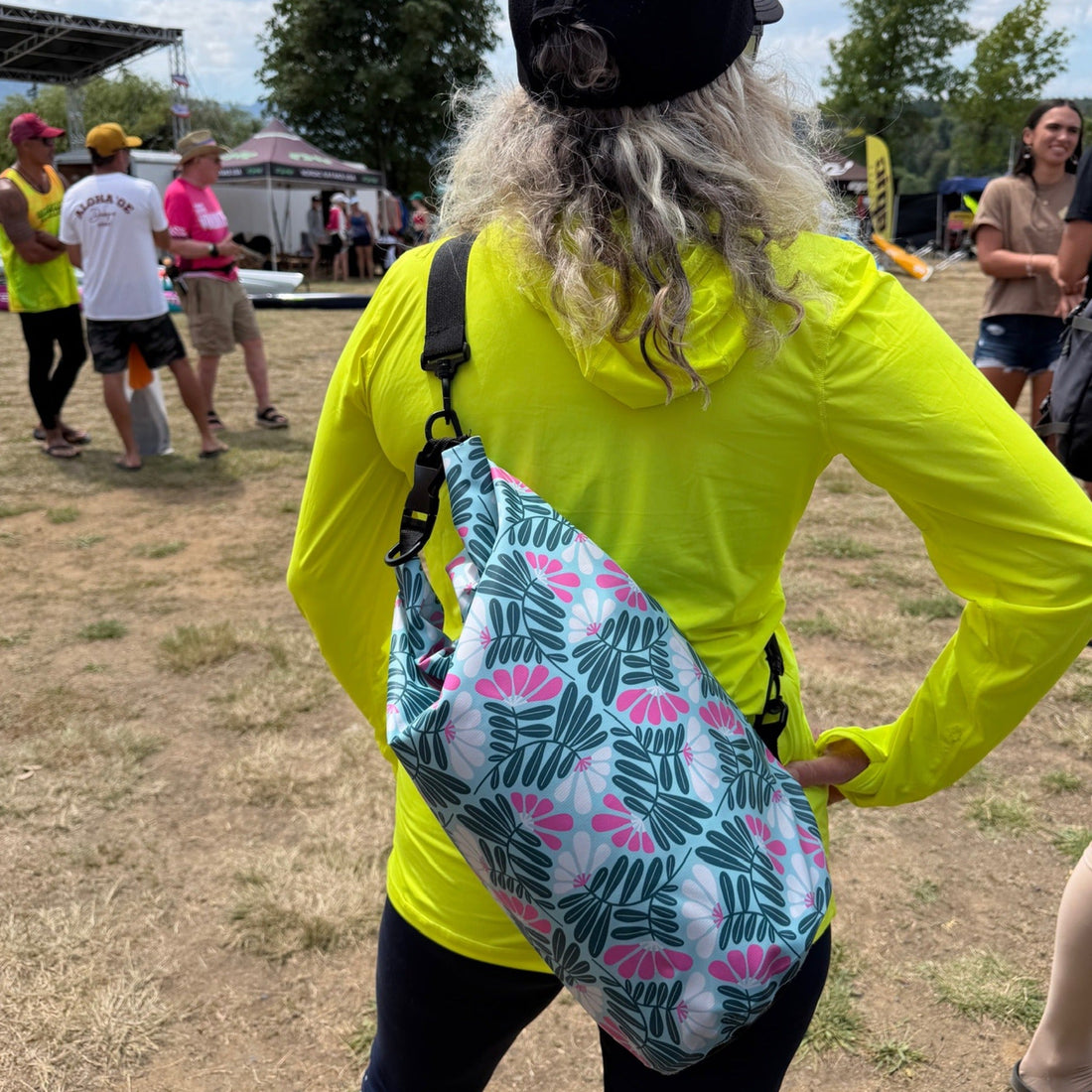 Woman in bright neon yellow shirt with a patterned dry bag slung over shoulder
