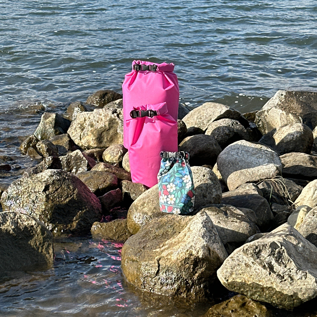 three dry bags on rocks next to a body of water