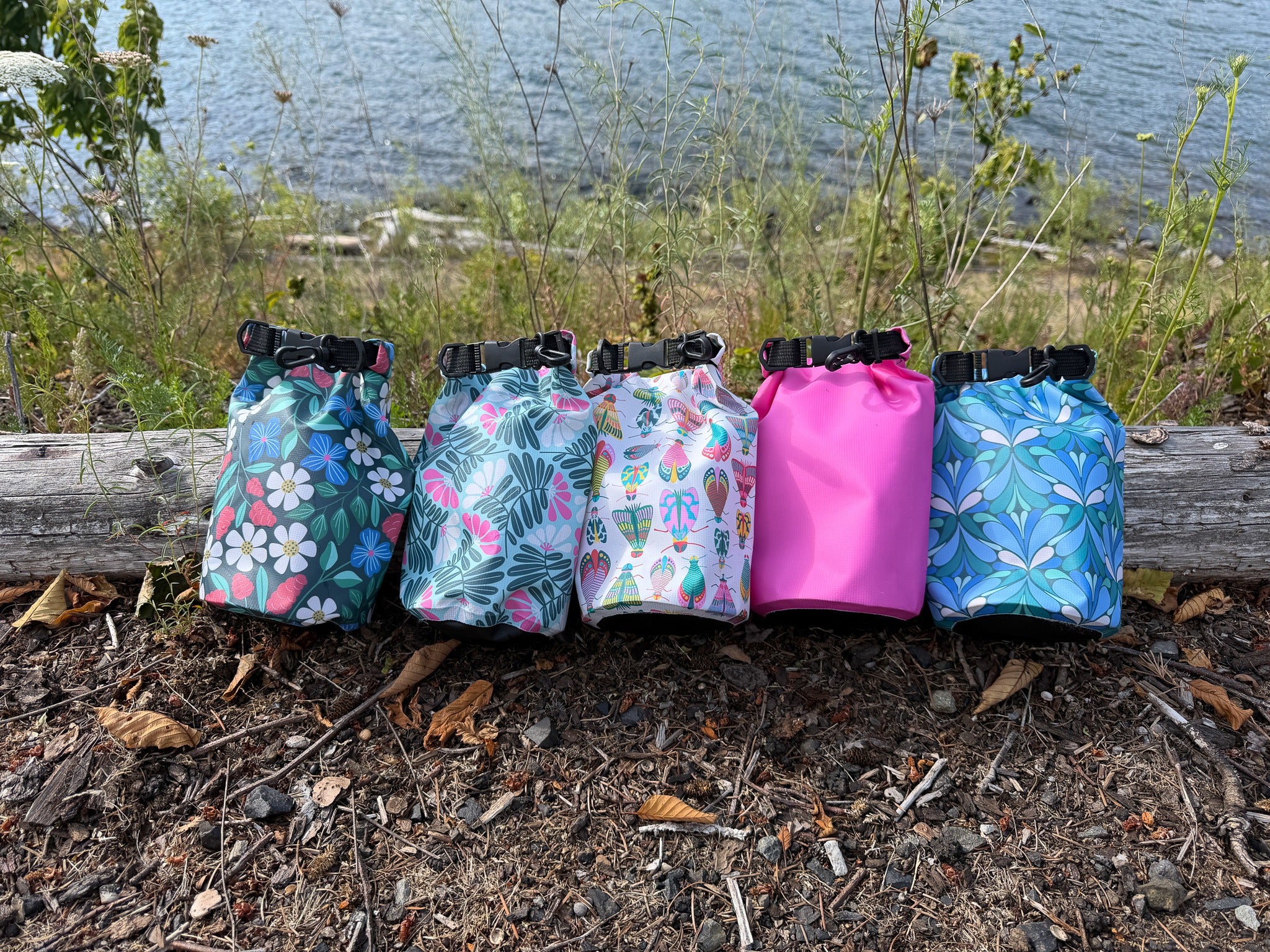 2L dry bags in a row next to a body of water
