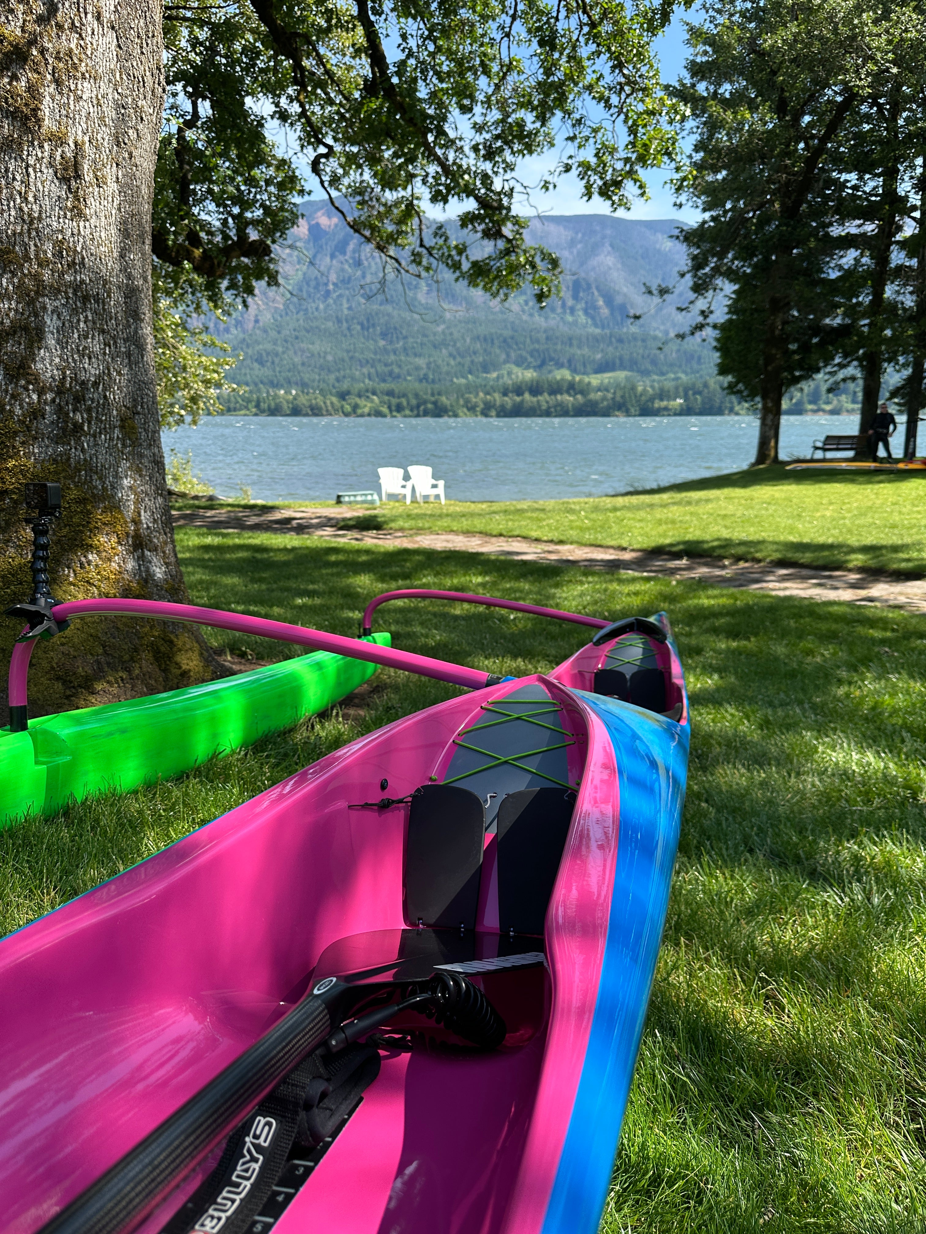 Pink and blue outrigger canoe on grass with the Columbia River in the background