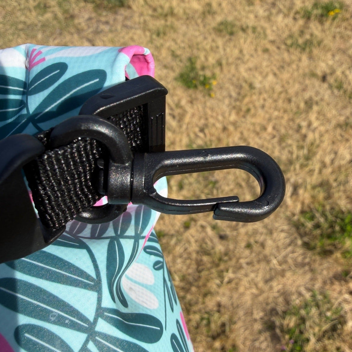 Blue and green floral dry bag clasp against dry gras