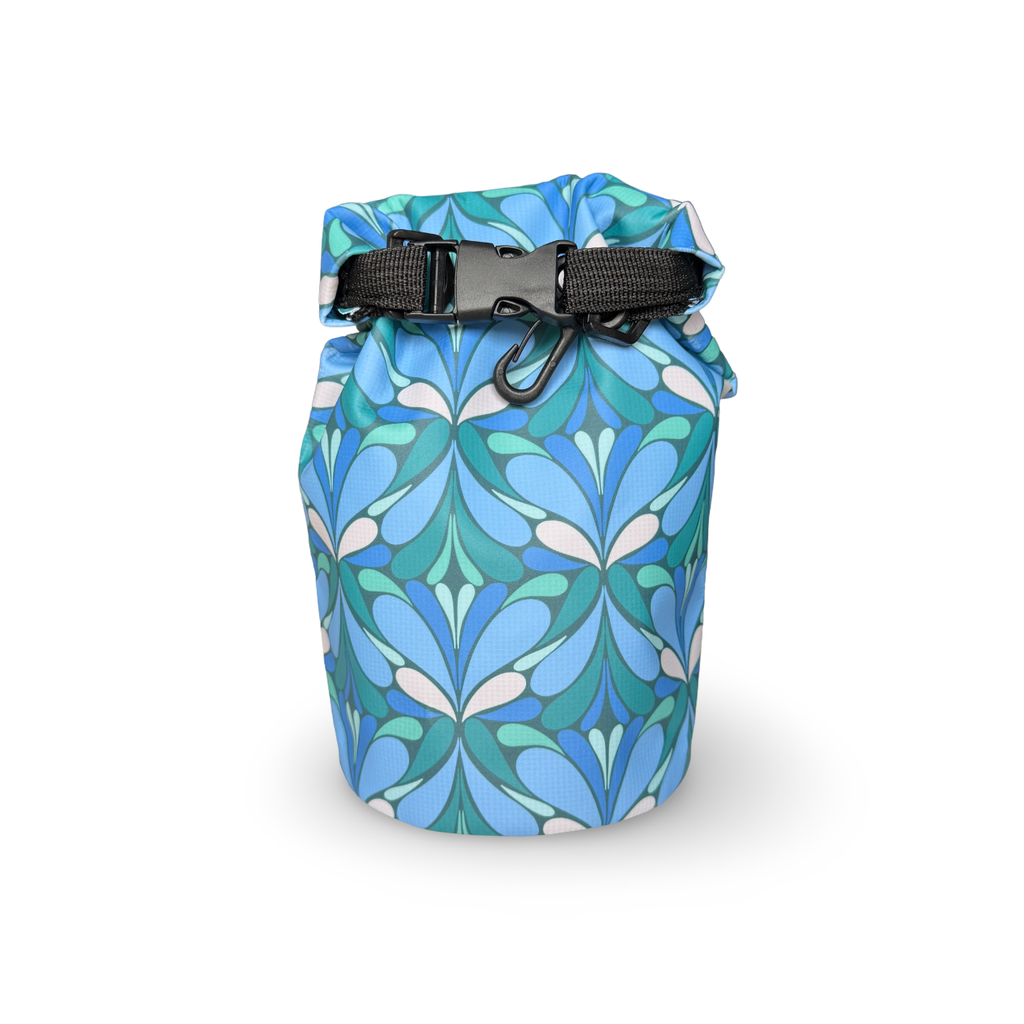 Wild Current dry bag in blue and teal geometric floral pattern waterproof dry bag with black roll-top buckle closure, isolated on a white background