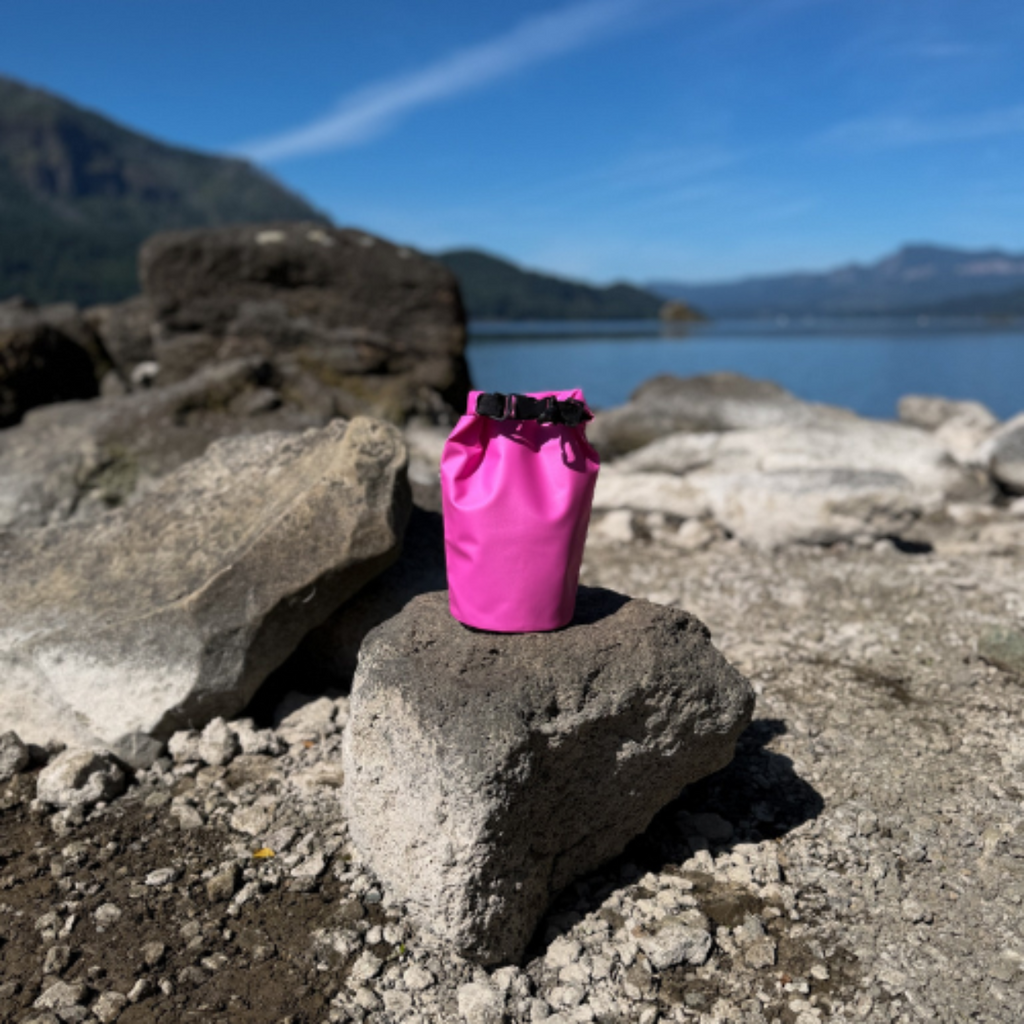 Pink dry bag on a rock with a mountain and lake in the background