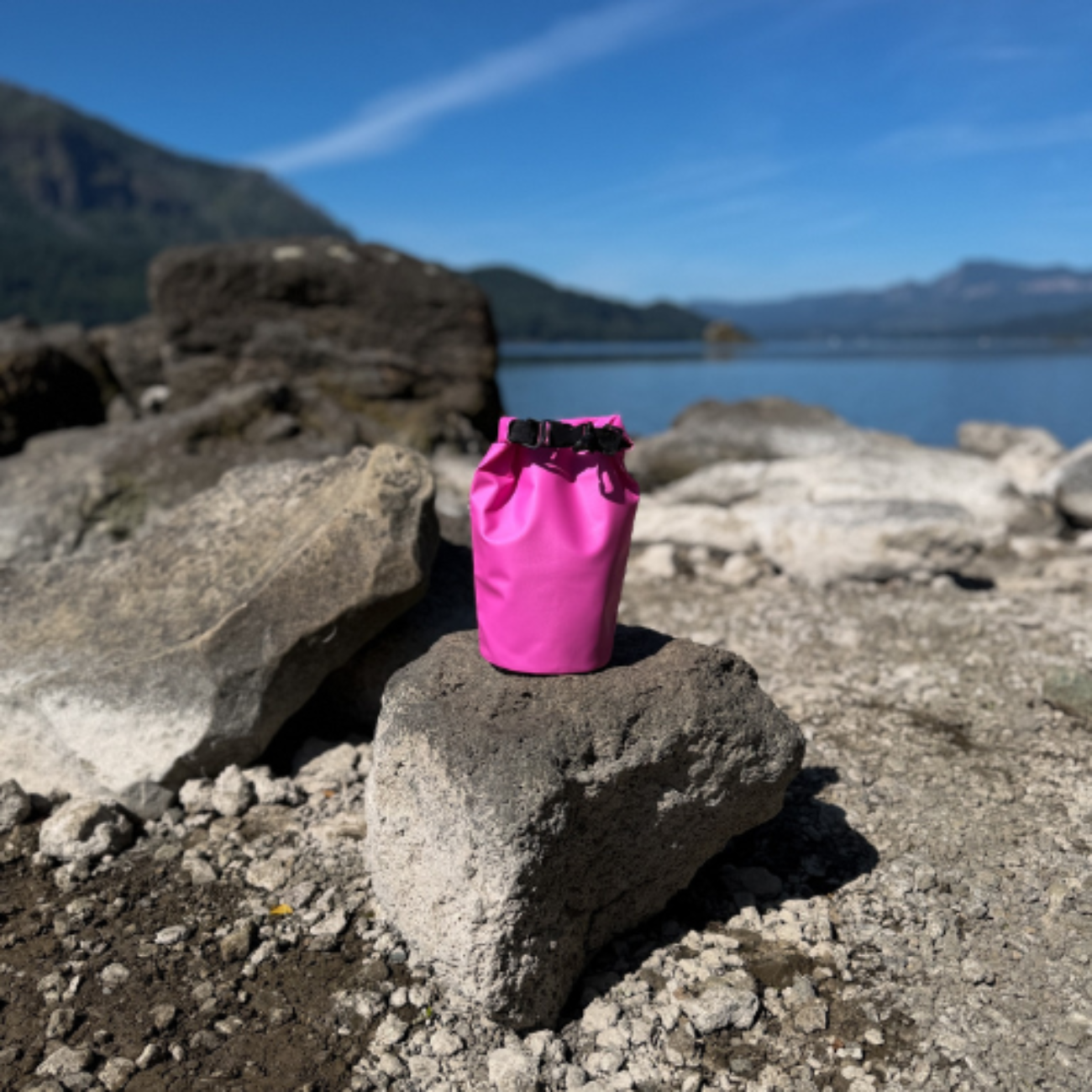 Pink dry bag on a rock with a mountain and lake in the background