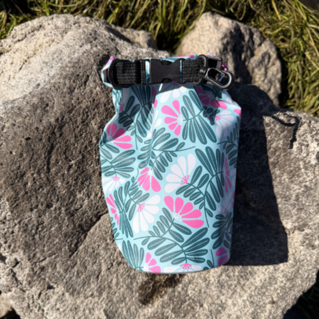 Durable floral and leaf pattern dry sack resting against a large textured gray boulder in direct sunlight.